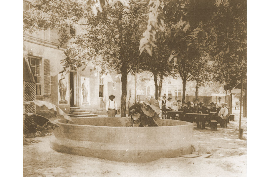 Looking west, this is the left wall of the Phoenix Saloon with San Antonio Street beyond the trees.  This fountain first appears in a Sanborn Insurance map of September 1891.